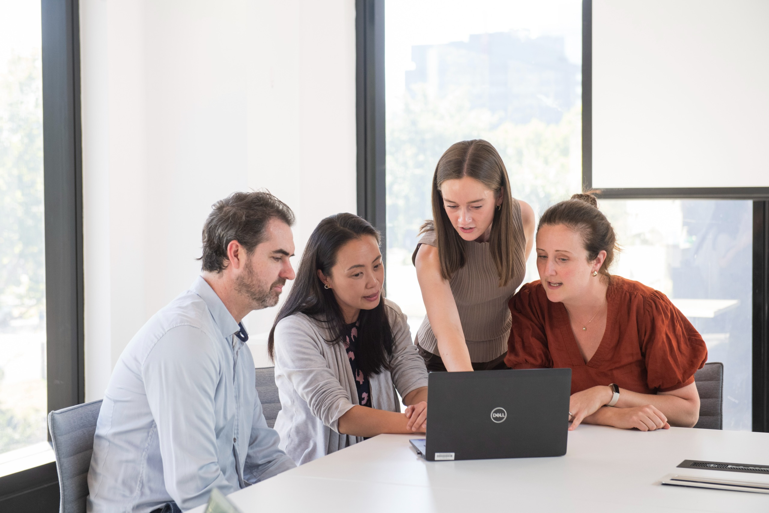 Four MUCTC team members sitting at a desk and viewing a laptop